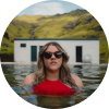 Donna in costume da bagno rosso e occhiali da sole che si gode una piscina di acque termali naturali in Islanda.