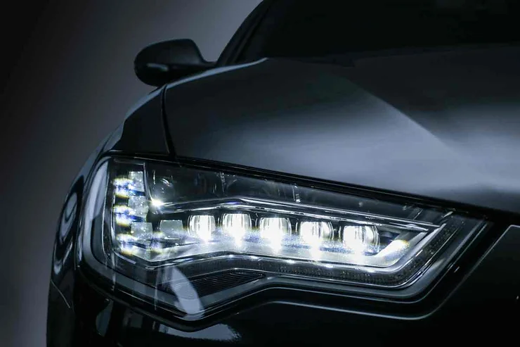 Primo piano di un faro a LED di un'auto nera, con design moderno e luce brillante.