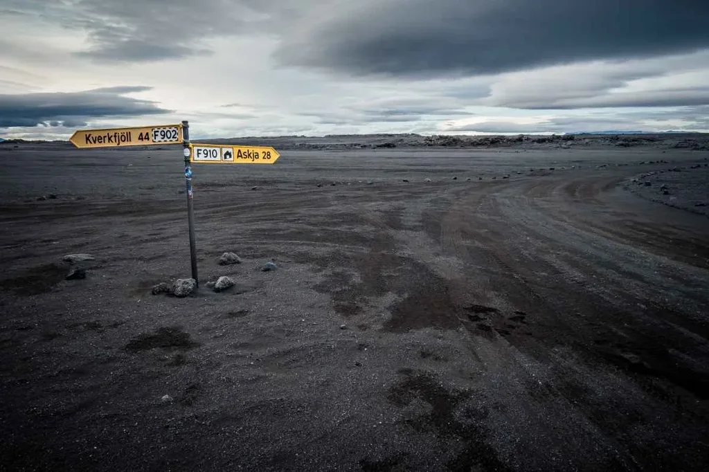 Navigare sulle strade F nelle Highlands islandesi Un cartello stradale che indica la direzione per Kverkfjöll e Askja, situato in un paesaggio vulcanico isolato con un cielo nuvoloso sopra.