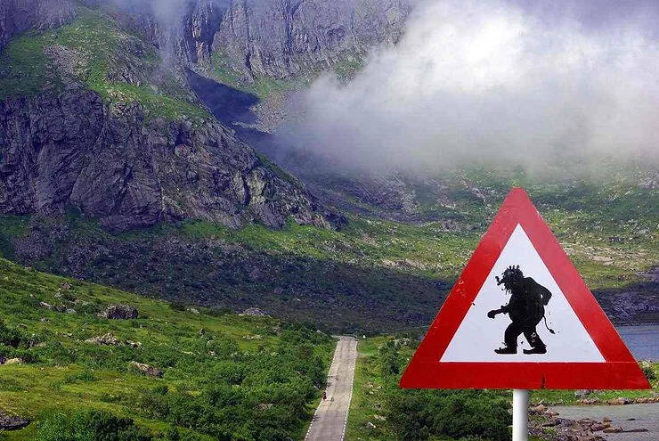 Cartello stradale islandese con figura di troll in primo piano.