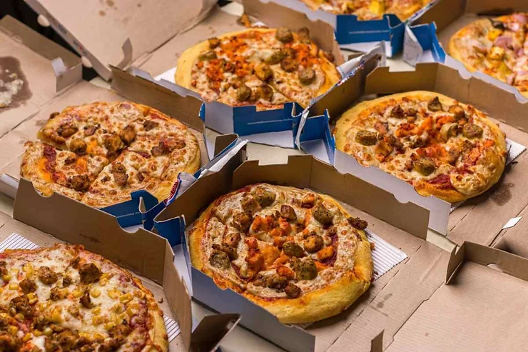 Diverse pizze appena sfornate servite in scatole di cartone pronte per essere condivise.