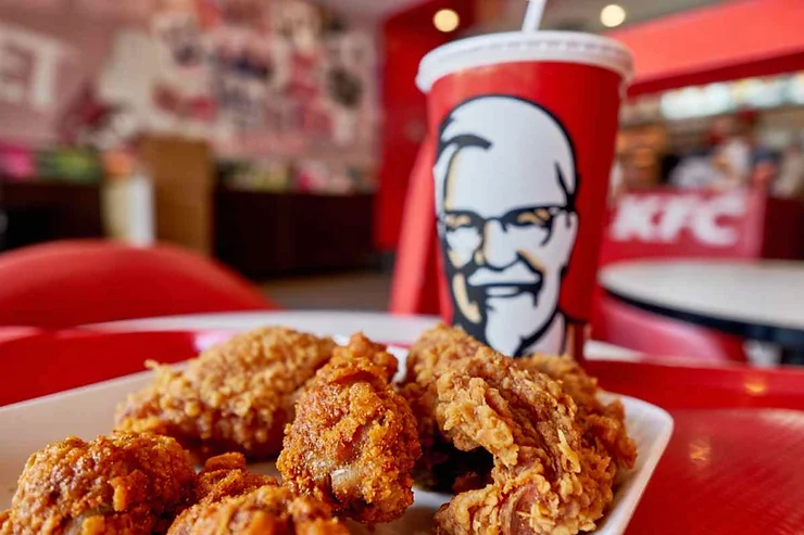 Un piatto di pollo fritto accompagnato da una bibita in un bicchiere del marchio KFC.