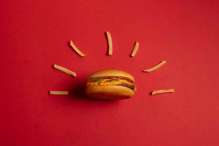 Un hamburger classico con patatine fritte disposto artisticamente su uno sfondo rosso.