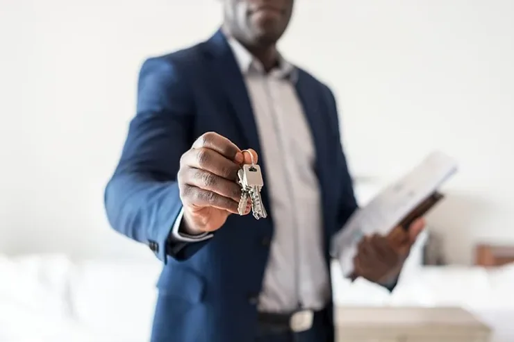 Agente immobiliare che offre una chiave per una nuova casa, simboleggiando il processo di acquisto e vendita di proprietà in Islanda.