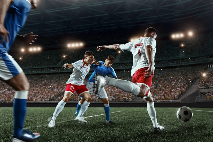 Un'epica scena di una partita di calcio con giocatori che si sfidano sul campo. Un'atmosfera vibrante con il pubblico in sottofondo che esalta l'azione sportiva. Perfetto per contenuti su sport e competizioni.