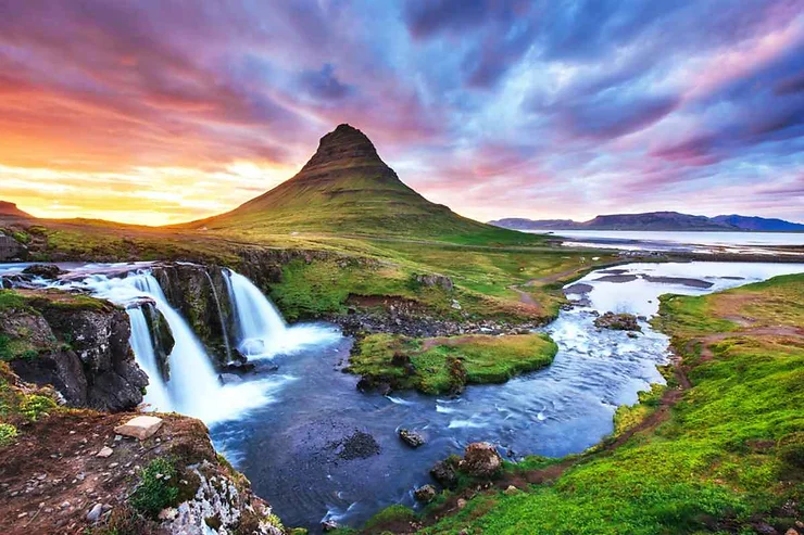 Cascata scenografica con il monte Kirkjufell al tramonto, colori vividi e atmosfera tranquilla.