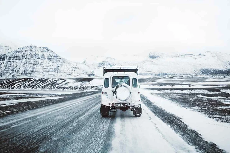 Una strada coperta di neve che si estende attraverso un paesaggio ghiacciato con montagne sullo sfondo.