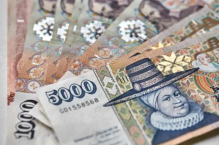  Diverse banconote da 5.000 e 1.000 corone islandesi disposte a ventaglio. In primo piano, un ritratto femminile con un cappello a tesa larga, che è un elemento distintivo delle banconote islandesi.
