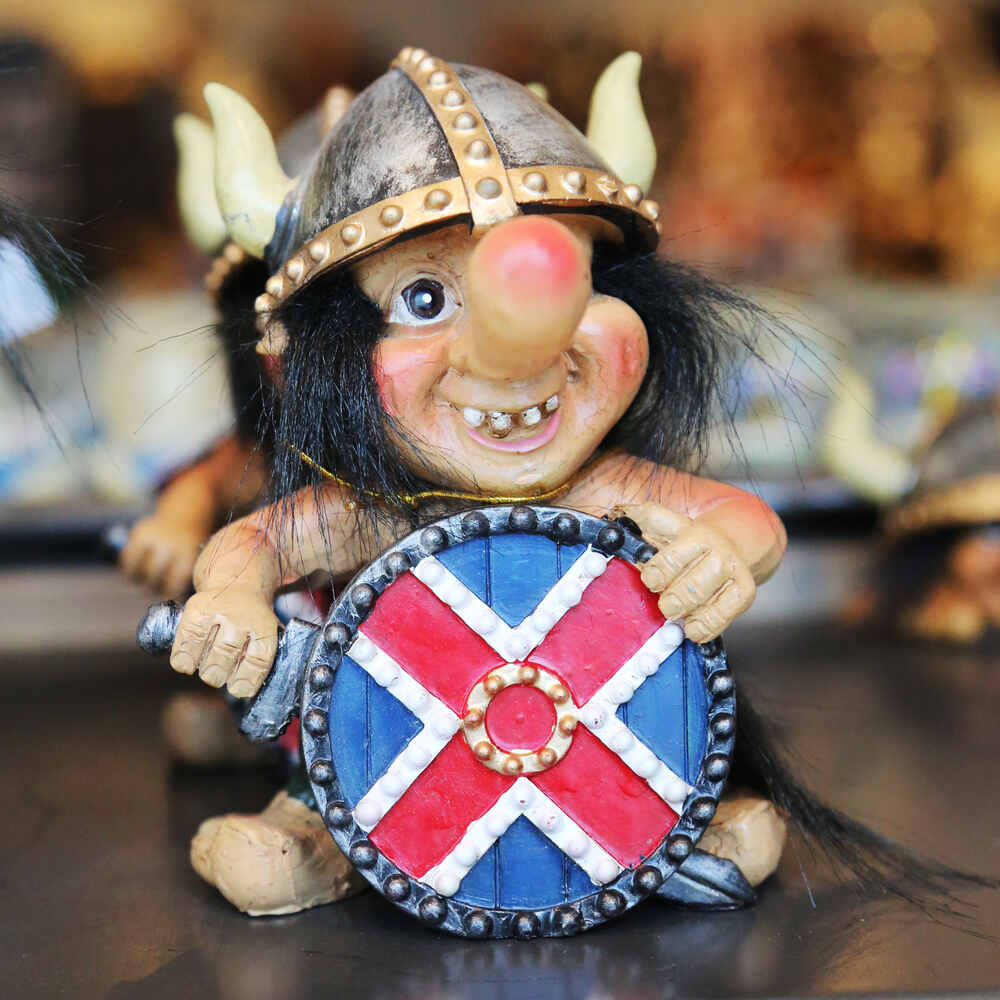 Il mercato delle pulci di Reykjavik Una statuetta raffigurante un troll con un casco da vichingo e uno scudo colorato con una croce blu e rossa. Il troll sorride mostrando i denti.