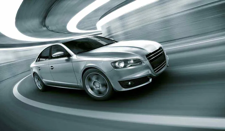 Un'auto sportiva argentata mentre percorre un tunnel moderno e curvo con linee di luce che evidenziano il movimento e il design aerodinamico.
