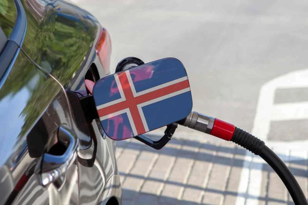 Auto in fase di rifornimento presso una stazione di servizio con la bandiera islandese esposta sul tappo del carburante, a rappresentare i viaggi e i trasporti in Islanda