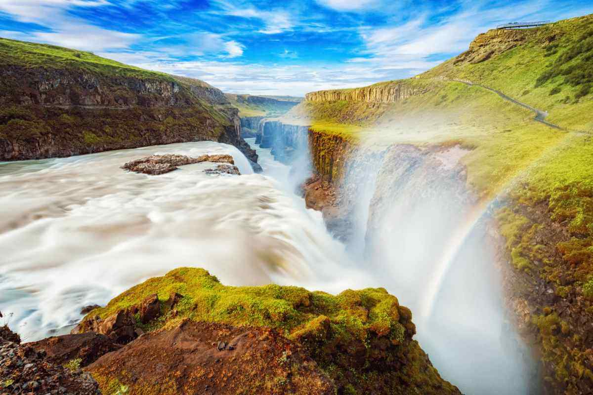 La cascata Gullfoss in Islanda con un arcobaleno tra gli spruzzi, incastonata in una gola rocciosa lungo il famoso itinerario del Golden Circle.
