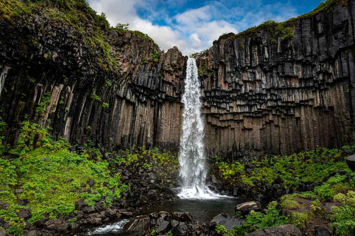 La cascata Svartifoss in Islanda, incorniciata da colonne di basalto nero nel Parco Nazionale di Skaftafell, tra vegetazione e formazioni vulcaniche.