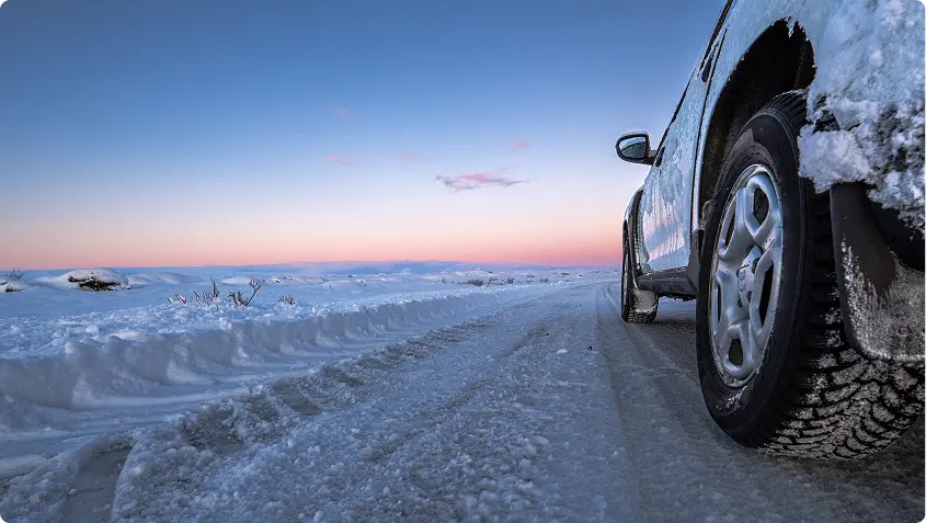 Vista aerea di una strada che attraversa campi di lava scuri con acque geotermiche blu vibranti nelle vicinanze, mostrando i paesaggi unici accessibili da Reykjavik con un'auto a noleggio.