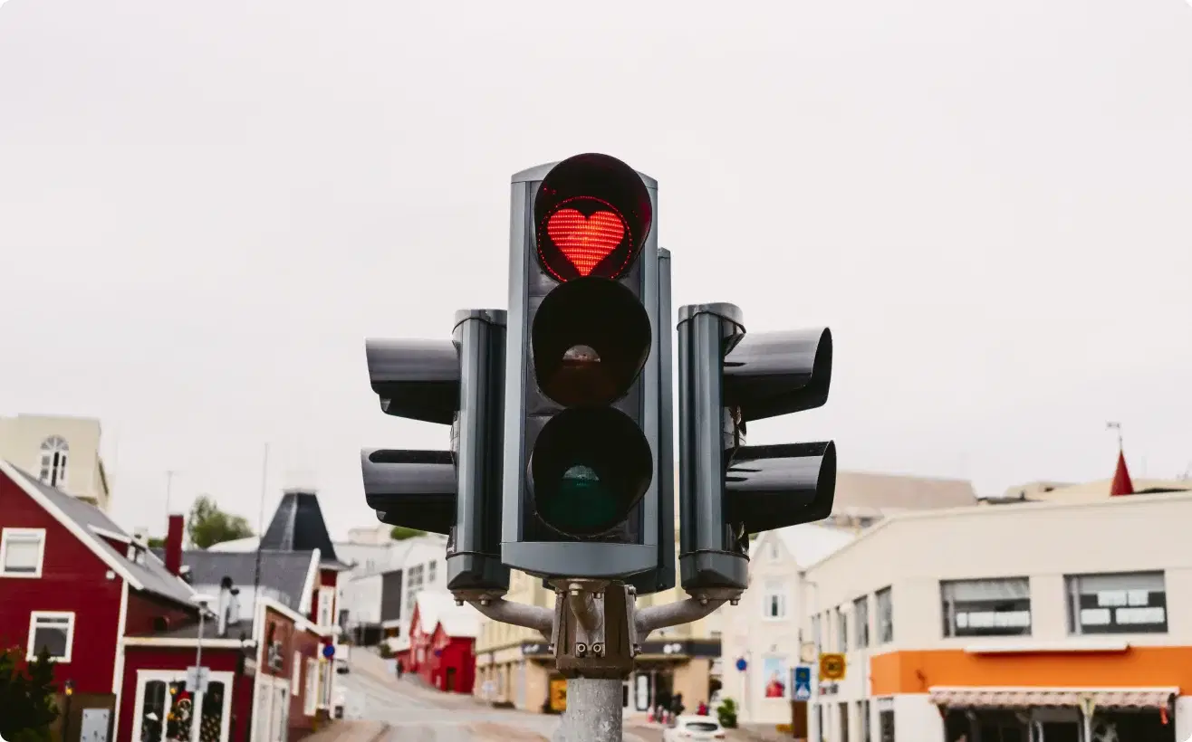 Semaforo urbano con simbolo di cuore rosso, espressione della passione dietro la missione familiare di Cars Iceland dal 2013.