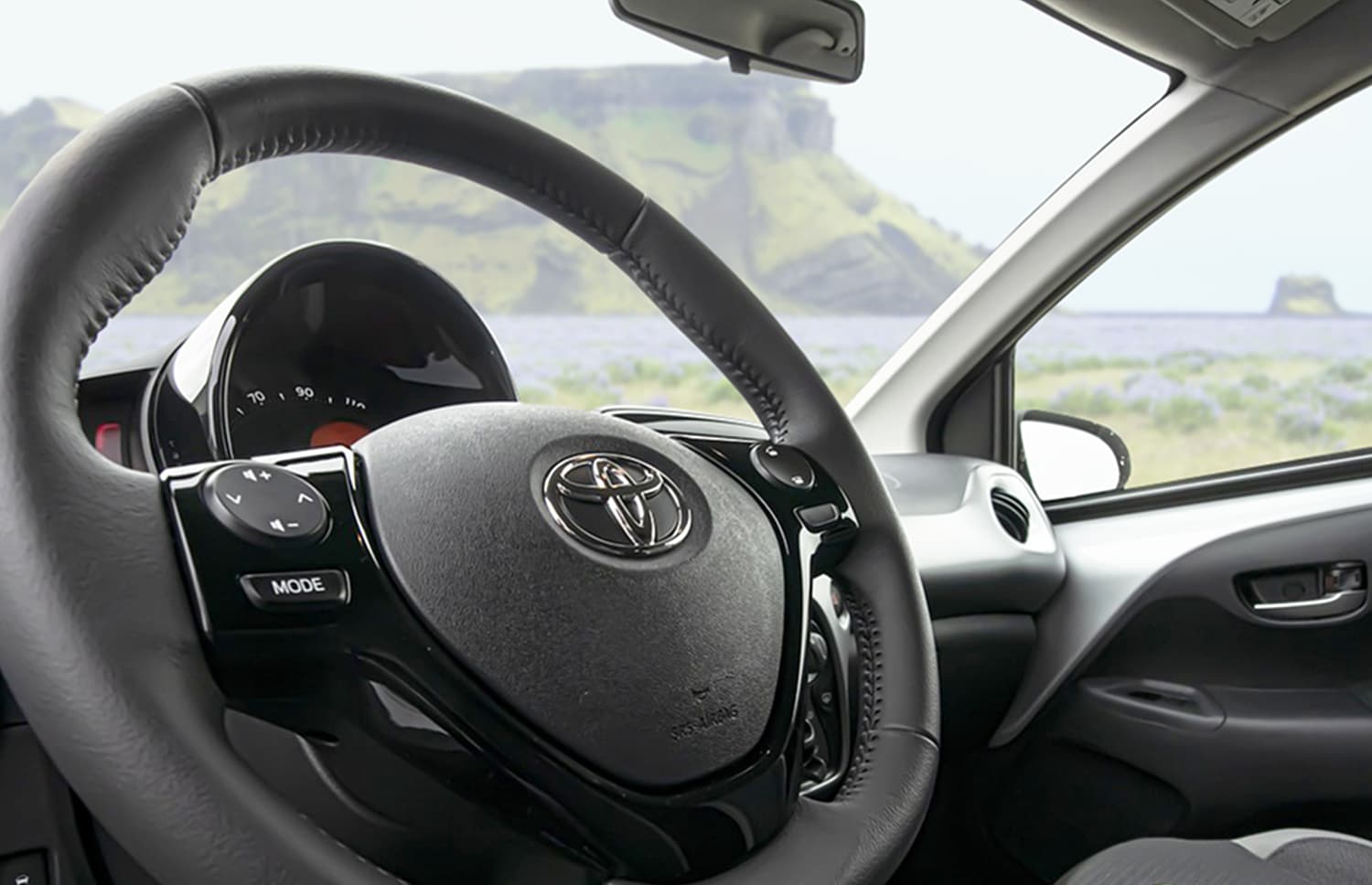 Toyota Aygo arancione brillante con cambio automatico, ideale per 4 passeggeri, compatta ed efficiente per girare le città islandesi.