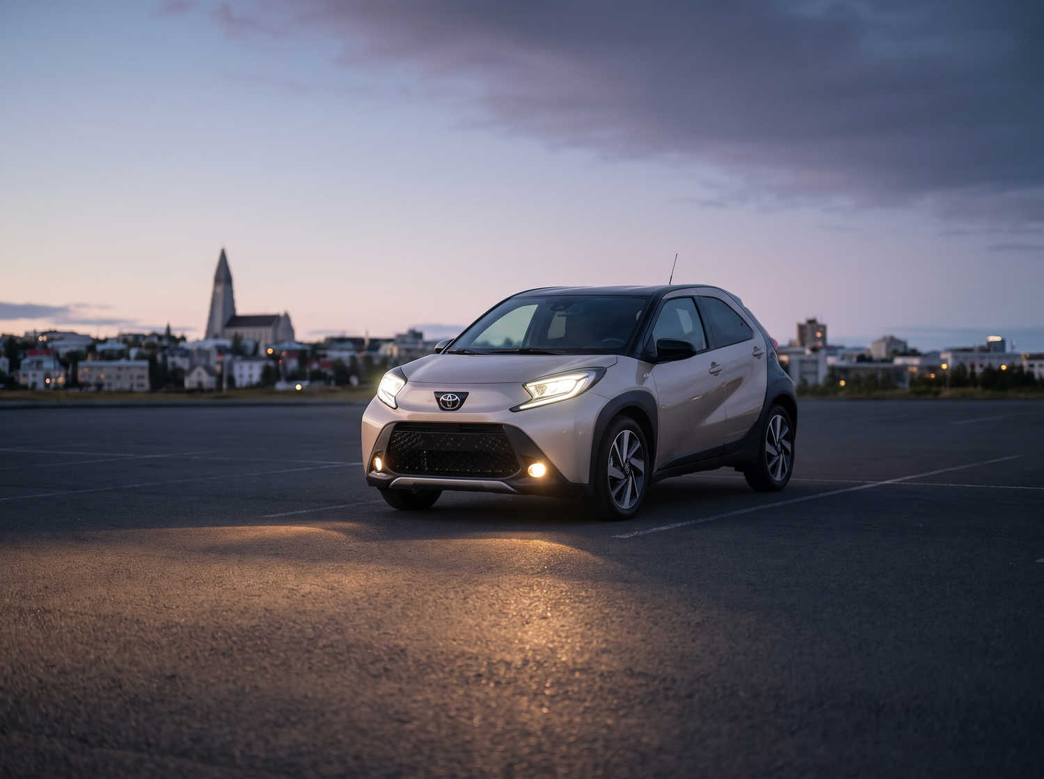 Toyota Aygo arancione brillante con cambio automatico, ideale per 4 passeggeri, compatta ed efficiente per girare le città islandesi.