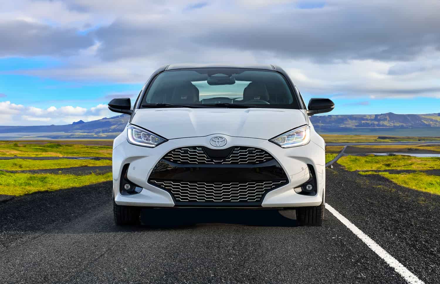 Toyota Yaris ibrida rossa con cambio automatico, 5 posti, GPS, retrocamera e spazio per 2 bagagli, ideale per viaggiare in Islanda.